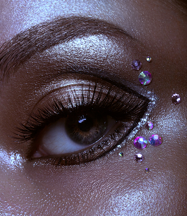 Dark skin with pigment highlighter and swarovski diamonds, close up macro eye photography