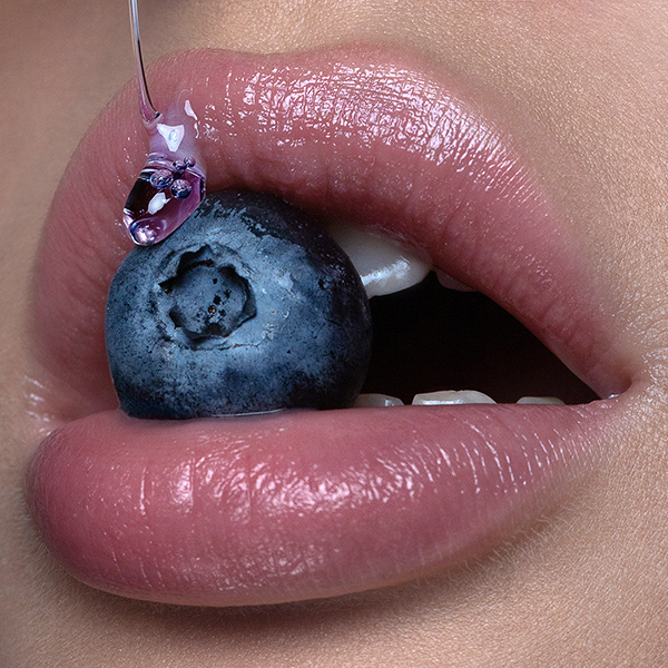 Beauty campaign of close up pumpy lips with liquid glass mac cosmetics and blueberry