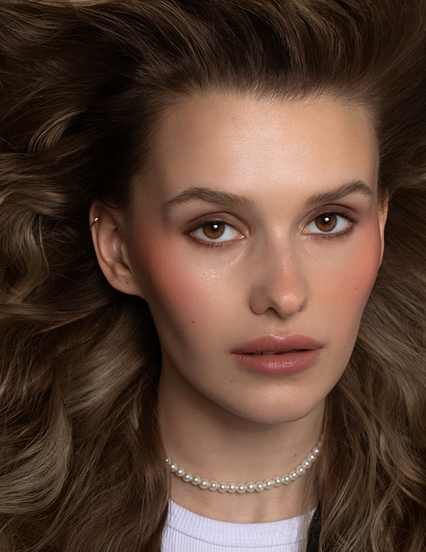 Beauty portrait of a brown-eyed girl with light makeup and extra-volume hairstyle